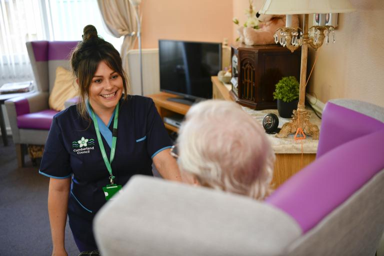 Carer smiles at older lady in armchair