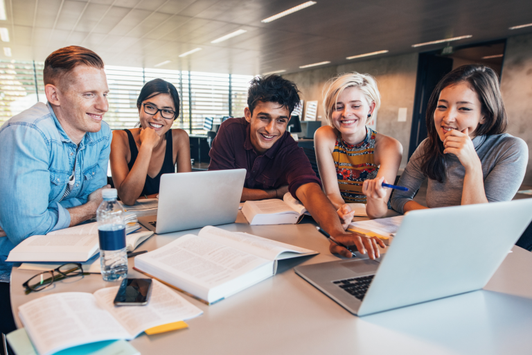 Young people sat with laptops, smiling