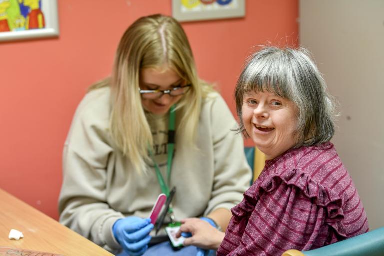 Young care worker supports lady with nail care