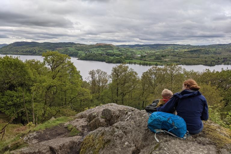 Woman with arm around young child looking out to mountains