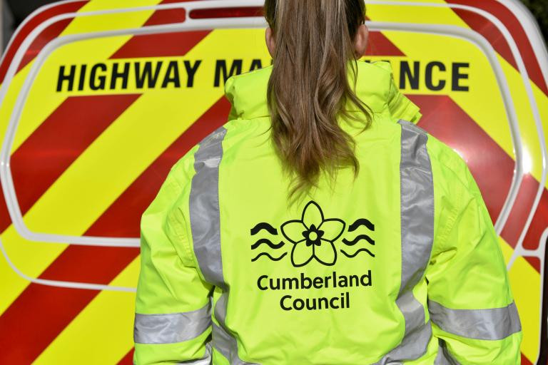 highway maintenance van with woman wearing high vis jacket with cumberland council logo