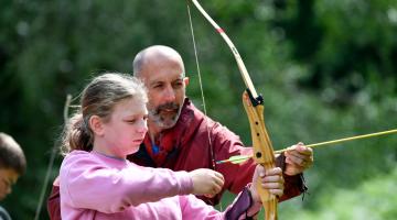 Man shows girl how to use bow and arrow